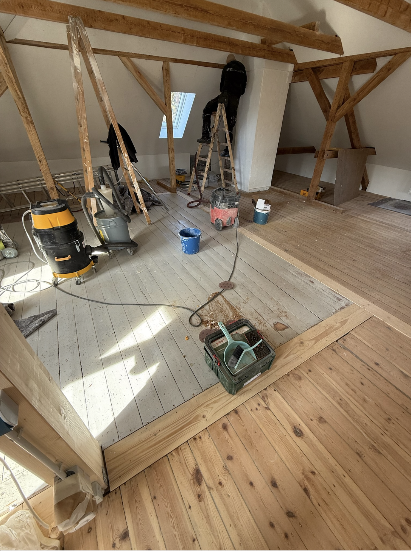 Holzaufwertung im Dachboden mit aufgearbeitetem Holzboden und Balken im Raum Berlin